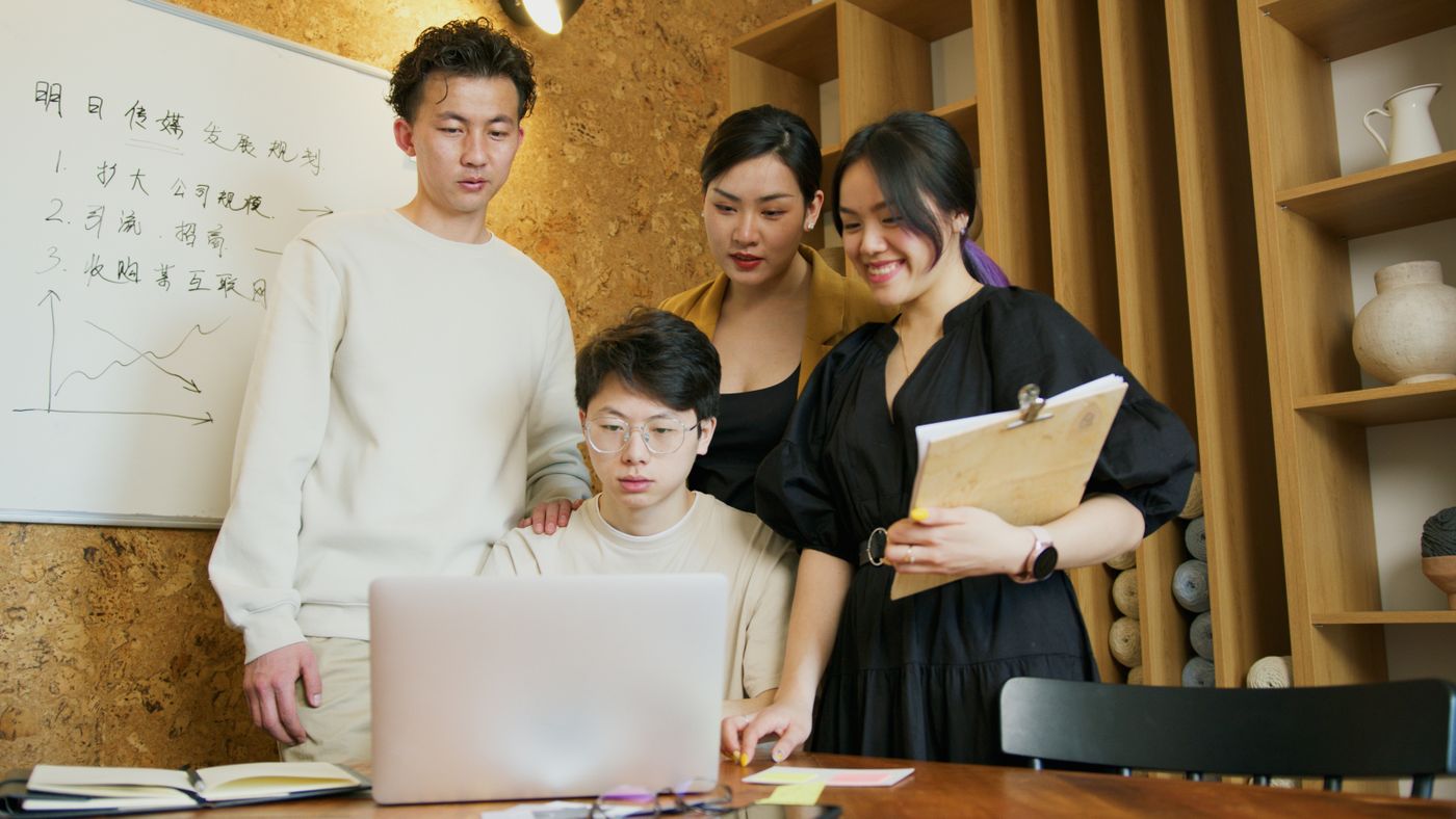 Students gathered around a laptop, working on a lab together